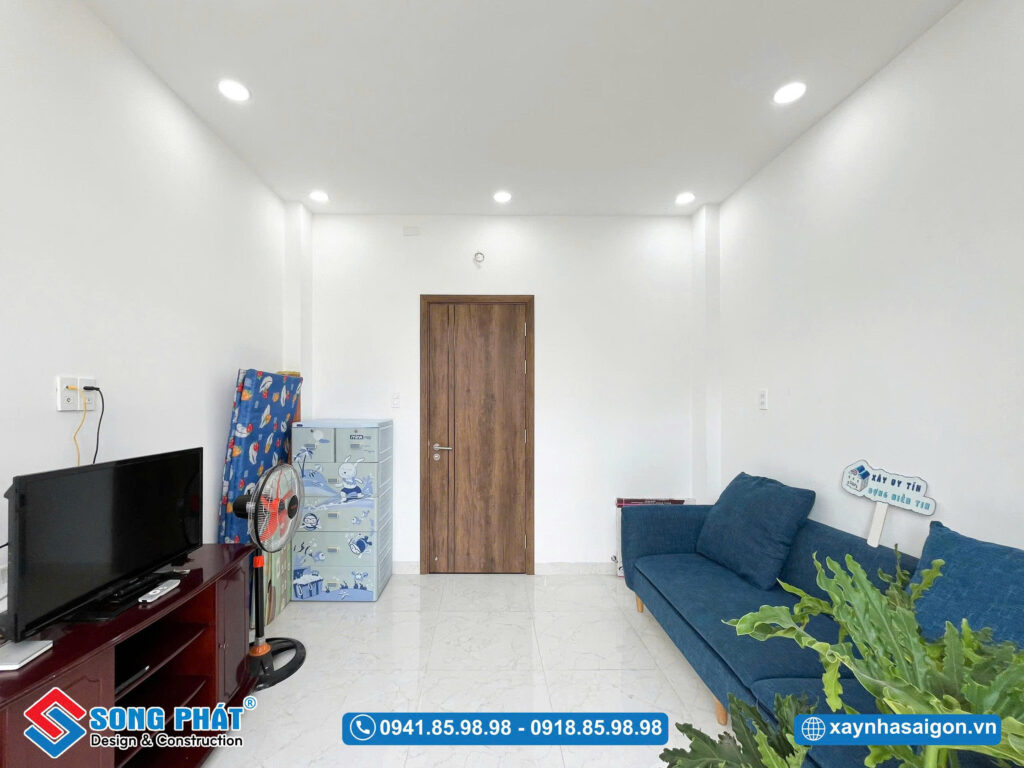 Không gian thư giãn với sofa, TV và ánh sáng tự nhiên từ ban công.